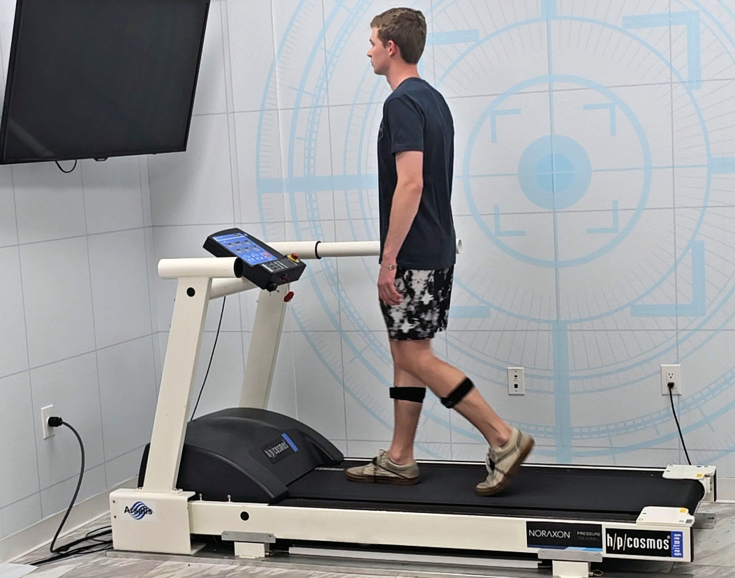 Treadmill Gait Analysis Participant seated in a chair in a biomechanics lab, wearing EMG sensors on the thigh to prepare for a sit-to-stand movement assessment.